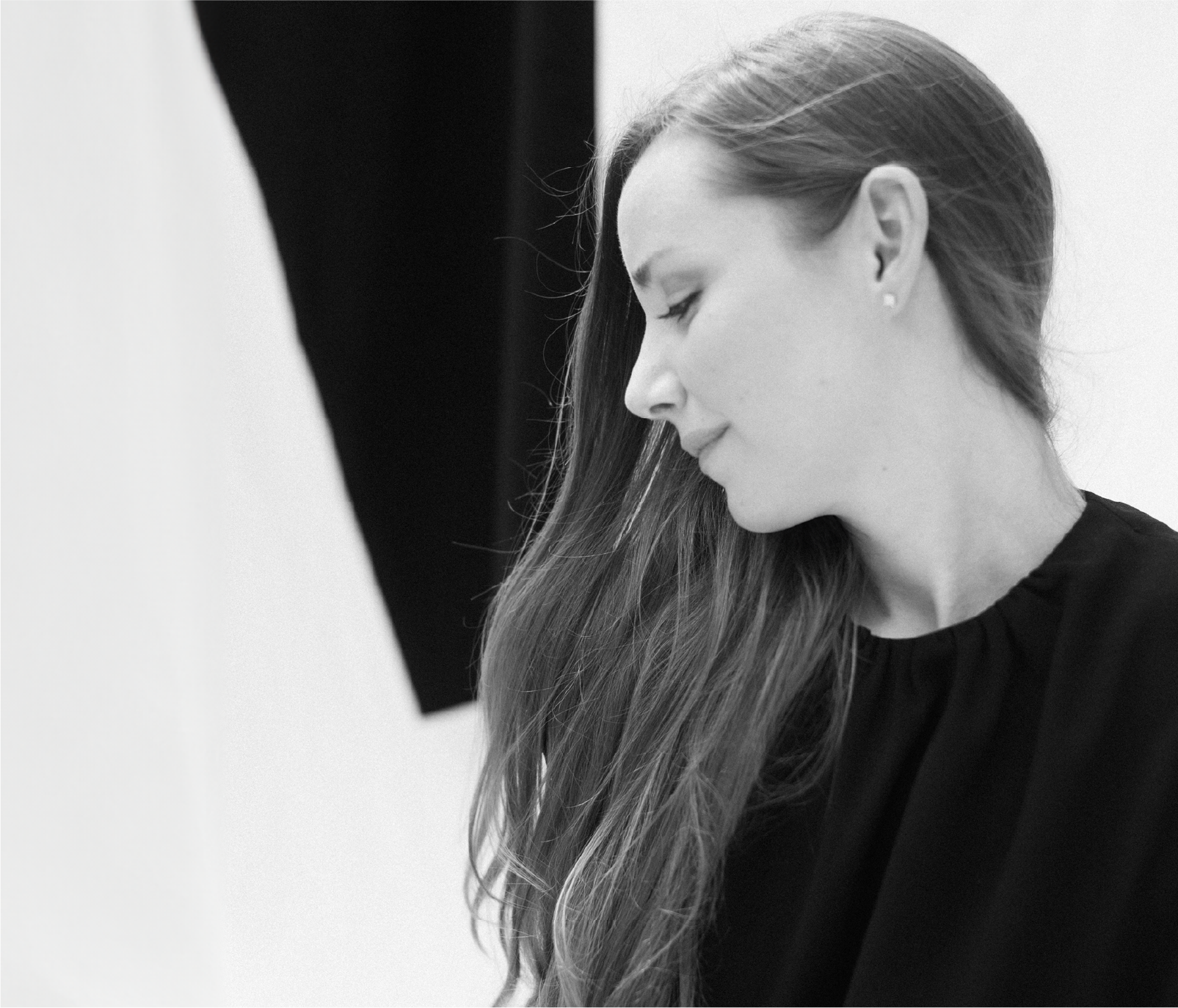 Portrait of founder Cassandra Kelley in natural light, looking down thoughtfully, her expression contemplative and serene, illuminated softly by the surrounding light