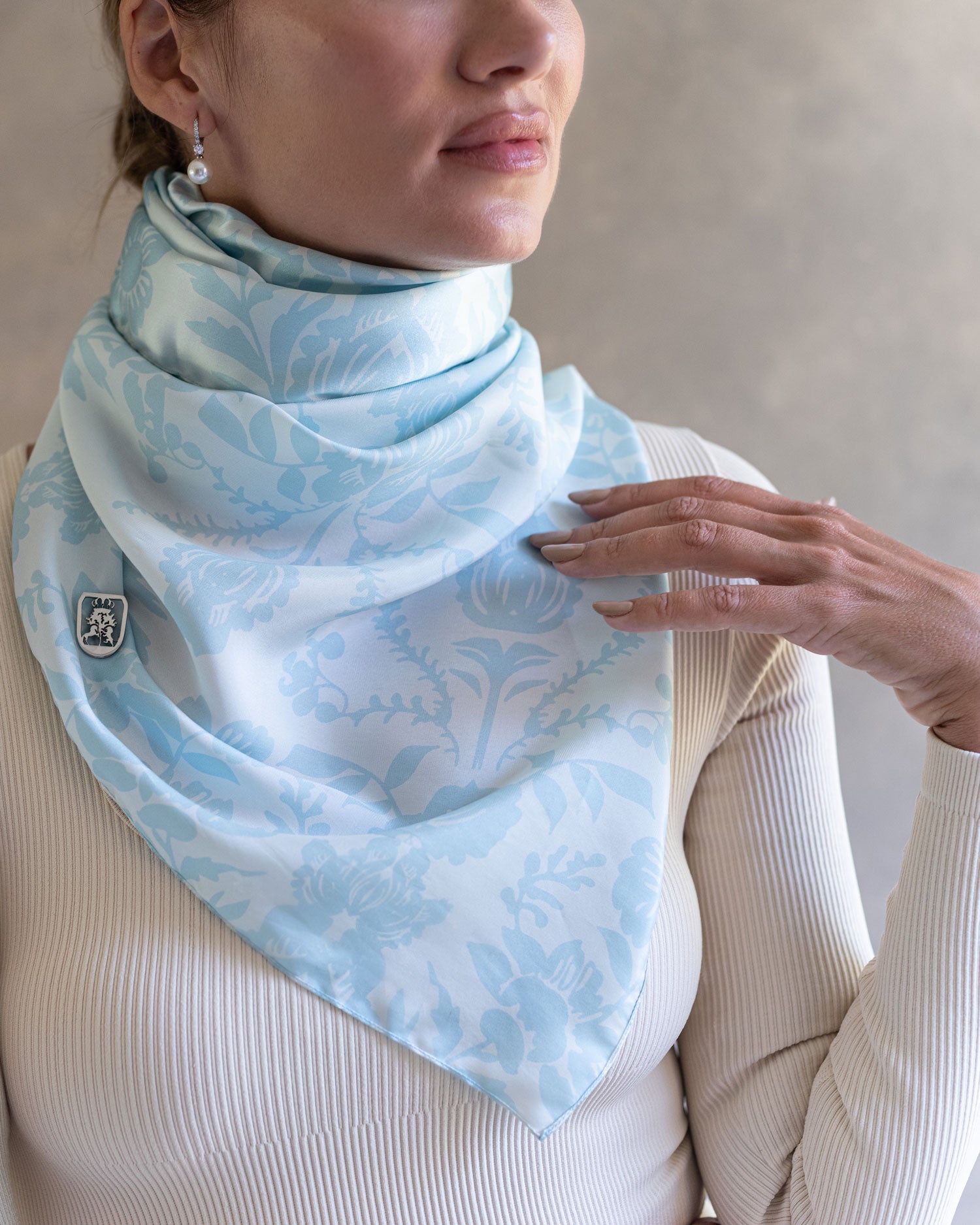 Close up of woman wearing a sky blue pareo as a sophisticated scarf as she gazes into the distance