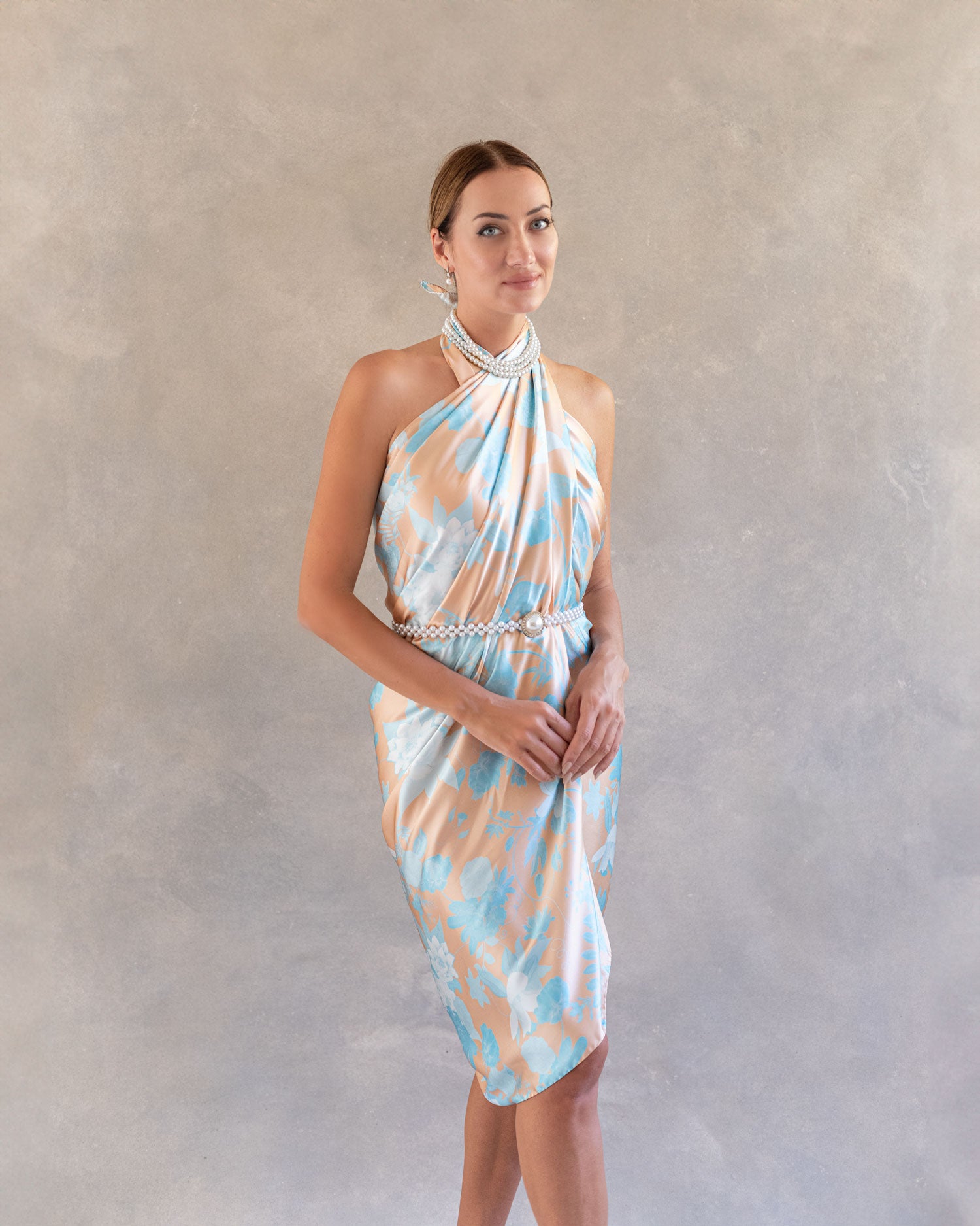 Front view of a woman in an orange and blue sarong pattern pareo, pattern in the style of Chinoiserie, styled as a dress, posing in an indoor studio