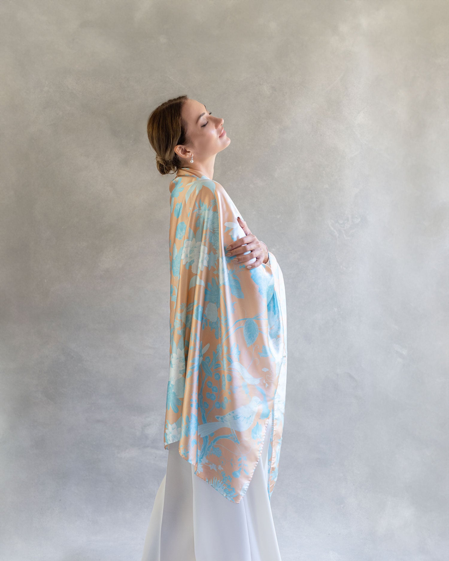 Woman looking serene wearing luminous silk pareo wrap as shawl, blue and orange, in the style of Chinoiserie 