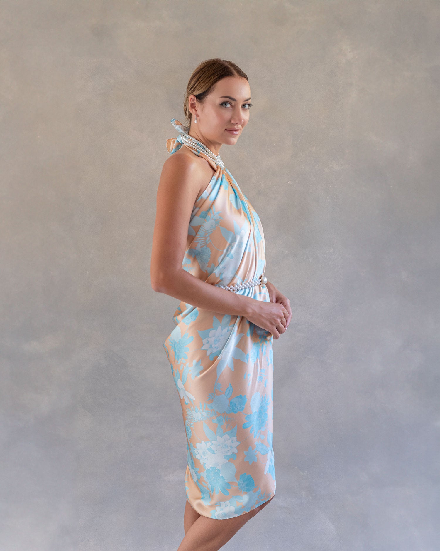 Side profile of a woman showcasing an orange and blue silk sarong pareo dress, highlighting its elegant drape