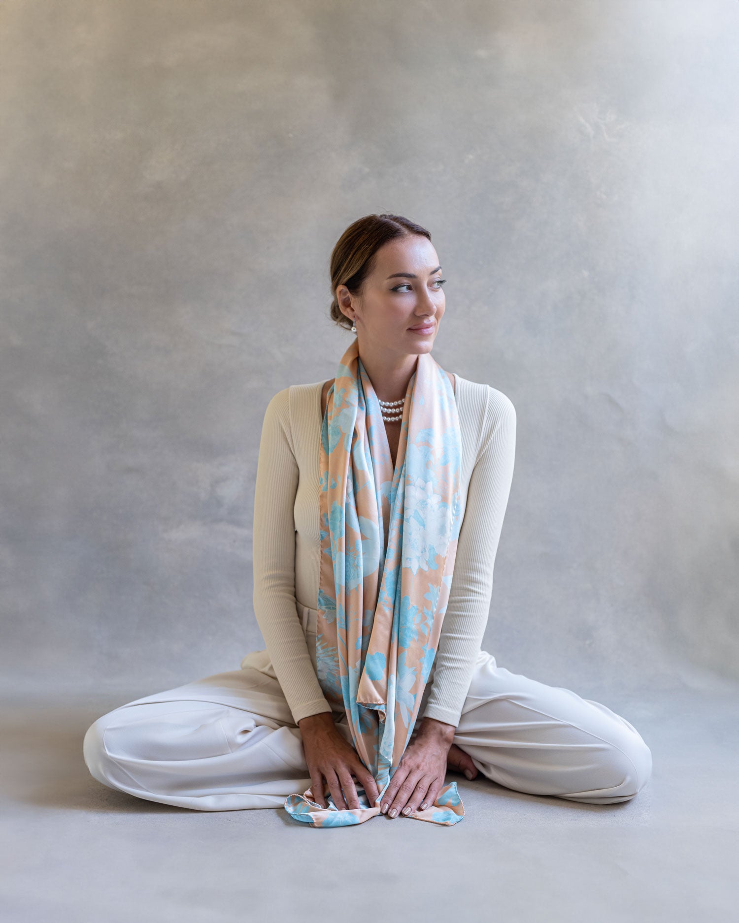 Woman seated on the ground wearing draped orange and blue scarf