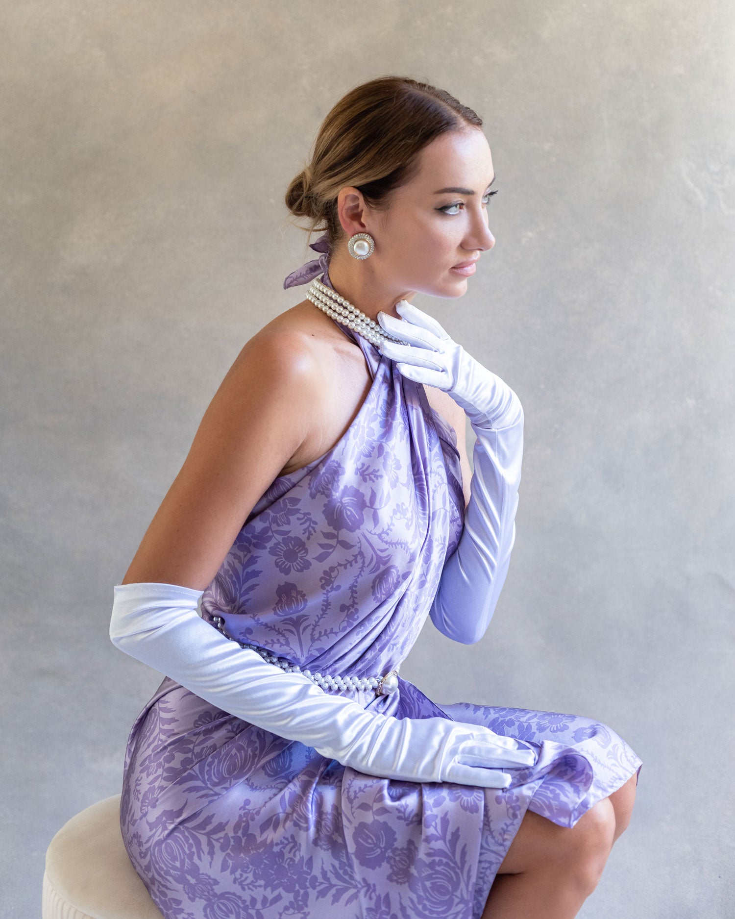 Elegant and stylish side view of a woman posing in a purple lavender sarong pareo dress, accented by long, dramatic gloves