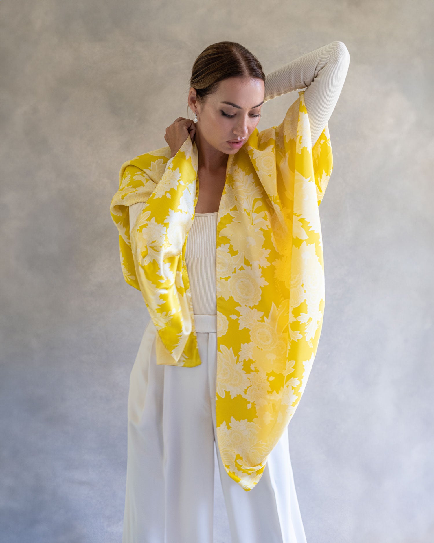 Woman in a vibrant, yellow sarong pareo styled as a casual shawl, showing the detailed flower and peacock pattern print