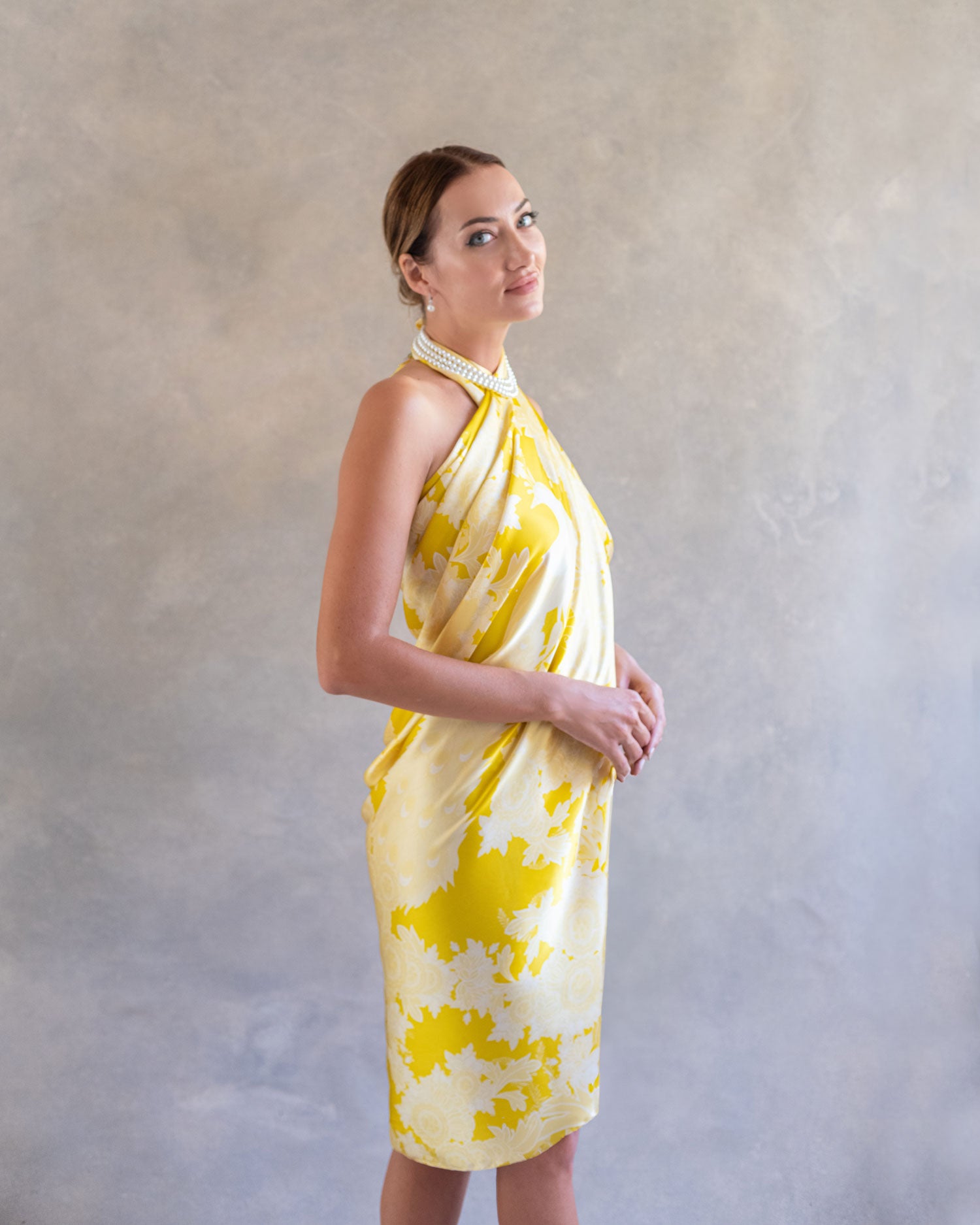 Side profile of a woman in a yellow pareo sarong dress, showcasing the vibrant print and fluid drape of the fabric